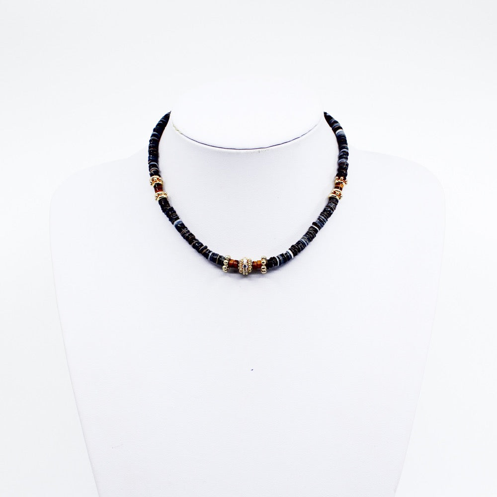 Black Tribal Puka. Stunning black puka mixed with gold plated spacers, gold plated spacers with cz detail, and brown beads. Handmade Jewelry. Stunning black and gold necklace. 16-18 inches in length. Shop Jewelry. MCHARMS. Women Necklace. Girl Necklace. Ocean Vibes. Gold Jewelry. Black Jewelry. Brown Jewelry. Miami. Miami Jewelry. Affordable Sustainable Jewelry. Affordable Prices. Jewellery. Jewelry stores. 