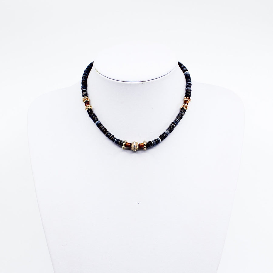 Black Tribal Puka. Stunning black puka mixed with gold plated spacers, gold plated spacers with cz detail, and brown beads. Handmade Jewelry. Stunning black and gold necklace. 16-18 inches in length. Shop Jewelry. MCHARMS. Women Necklace. Girl Necklace. Ocean Vibes. Gold Jewelry. Black Jewelry. Brown Jewelry. Miami. Miami Jewelry. Affordable Sustainable Jewelry. Affordable Prices. Jewellery. Jewelry stores. 